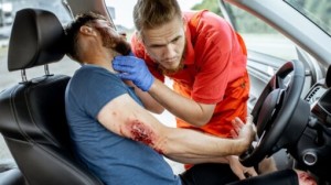 Person performing CPR chest compressions on a training manikin with an automated external defibrillator (AED) in use during a first aid training session.