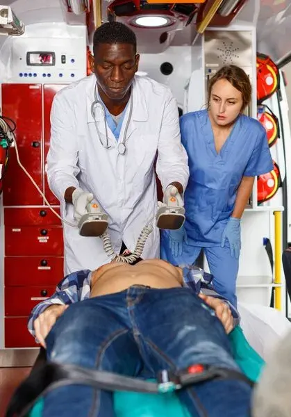 A paramedic and doctor prepare to use a defibrillator on a patient.