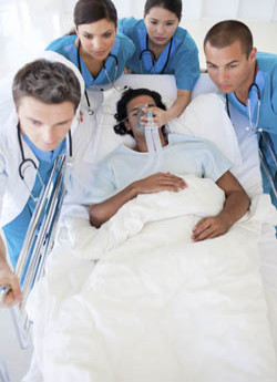 Medical team rushing a patient on a hospital bed, with the patient receiving oxygen through a mask.