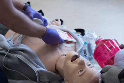 paramedics training on male mannequin with aed pads and bag ventilation