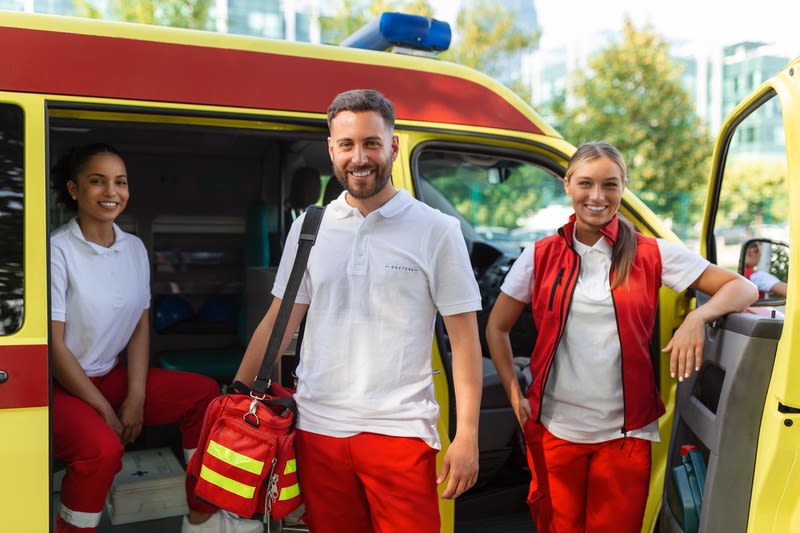 A male rescuer and 2 female rescuer in uniform stand by an ambulance for ACLS and ALS emergency response